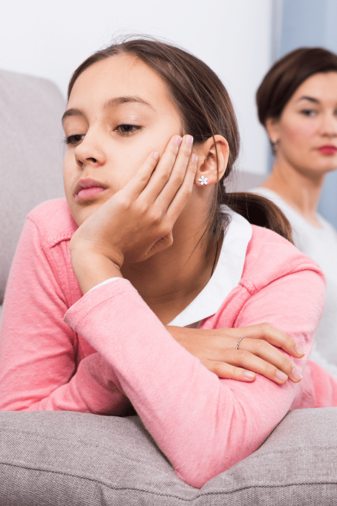 Parent patiently sitting near teen who seems withdrawn, showing support